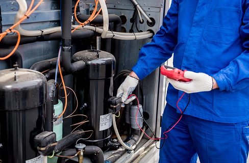 A service technician performs professional fridge repairs with a multimeter