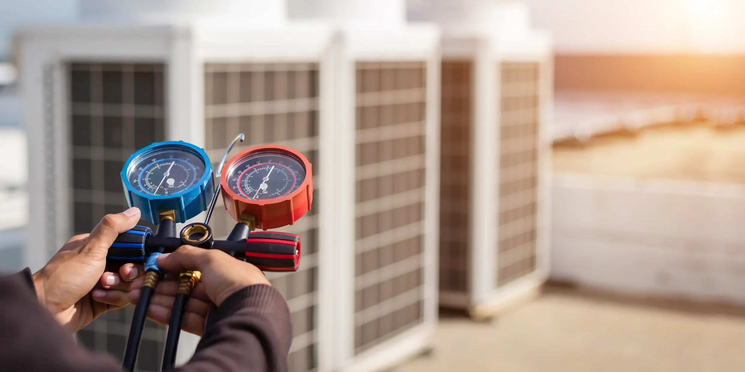A professional HVAC technician measures refrigerant pressure on a rooftop